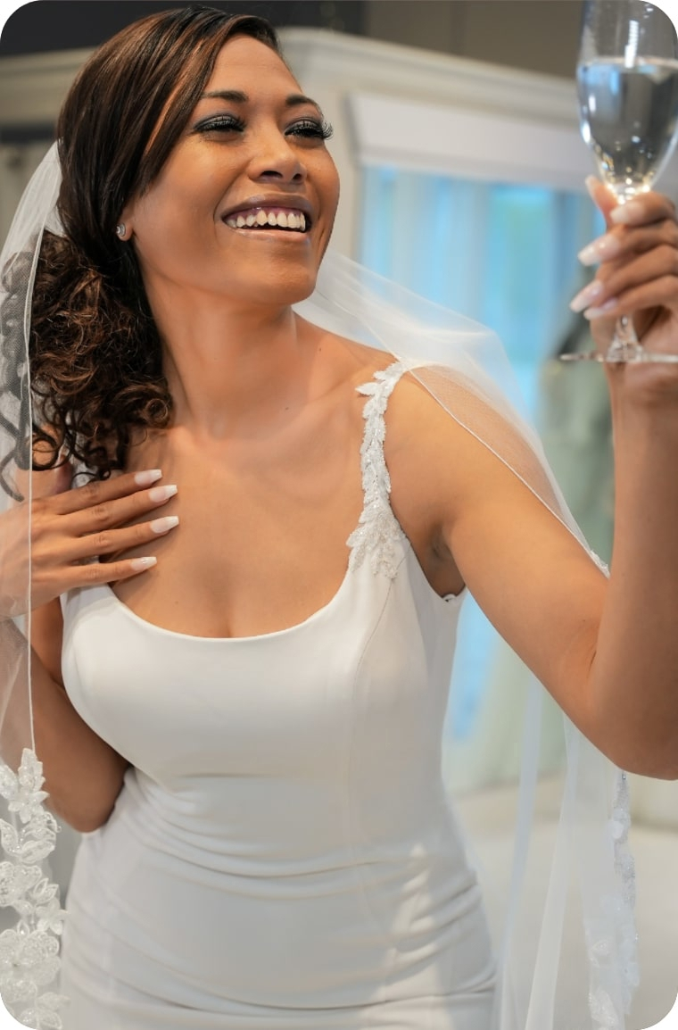 Model wearing white bridal gown with a glass of wine